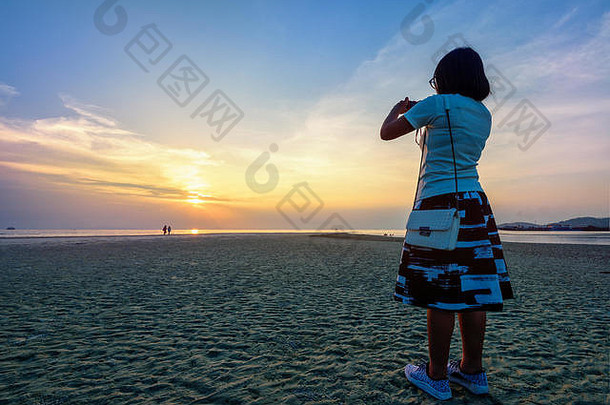 在南非的纳森日落视点，亚洲女游客在海滩上拍照，美丽的自然景观是五颜六色的天空和海洋