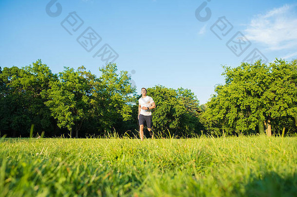 一个英俊的年轻人在一个夏天的晚上在公园里<strong>跑步</strong>。