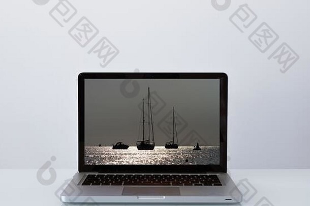打开带有日落时帆船图像的笔记本电脑