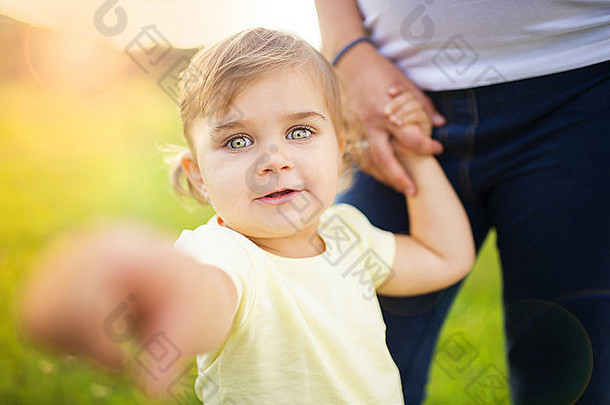 公园里快乐的小女儿牵着怀孕母亲的手的画像
