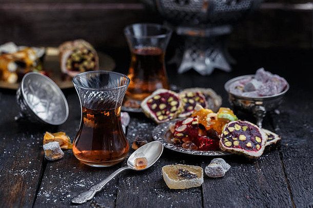 带正宗玻璃杯的土耳其茶。两杯土耳其茶和糖果，深色木质背景