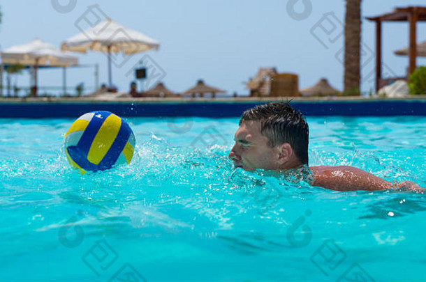 在一个阳光明媚的<strong>夏日</strong>，一个运动员在酒店的<strong>游泳</strong>池里<strong>游泳</strong>，试图接球