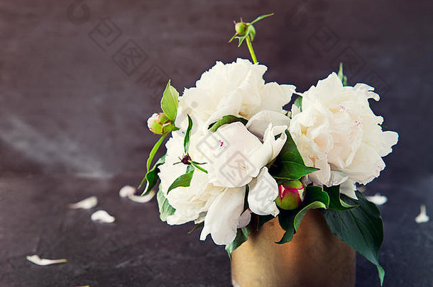 特写镜头：黑色石头背景上的复古碗中，白色牡丹的清新花束，花瓣。复古色调设计。结婚花。卡片