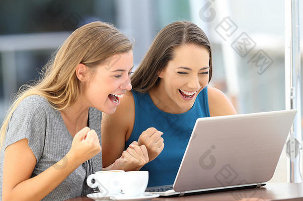 两个兴奋的朋友坐在餐厅阳台上的笔记本电脑里发现了在线内容