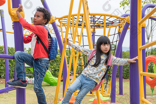 两个男孩和女孩在学校操场玩儿童攀岩玩具，返回学校活动。幼儿园