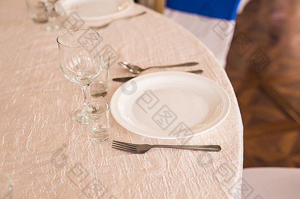 桌子上优雅的空盘子、餐具、餐巾和玻璃杯。