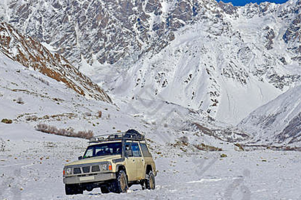 汽车在雪原上行驶，背景是积雪覆盖的山脉和冰川