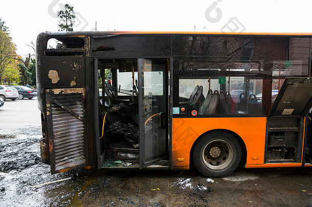 被烧毁的公共交通巴士在行驶中起火并被消防队员扑灭后出现在街道上。