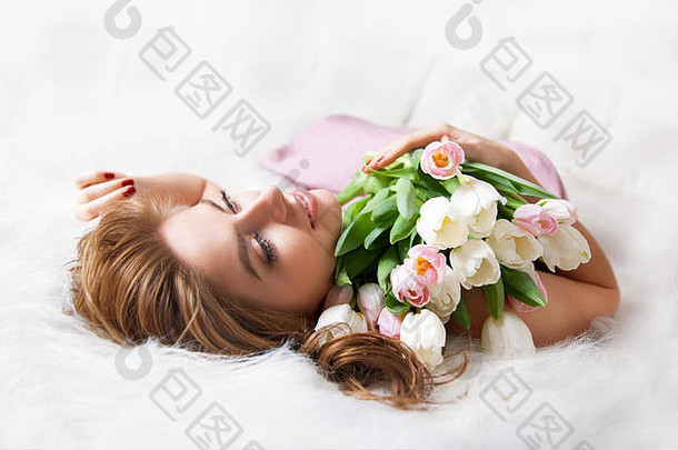年轻的女人花束花床上