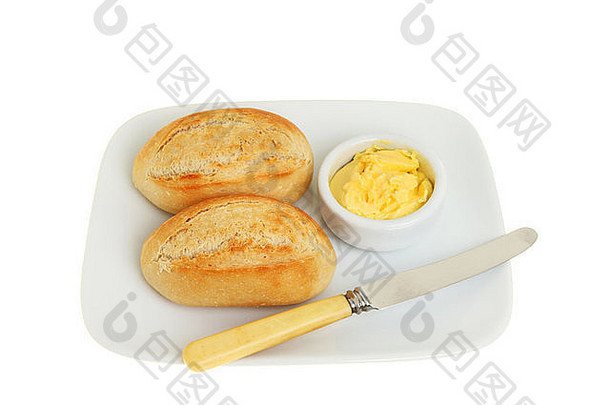 两个带黄油的小面包卷和一把刀放在盘子上，与白色隔离