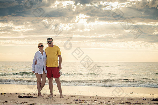 快乐成熟的夫妇中期五十多岁海滩温暖的颜色爽肤水自然光