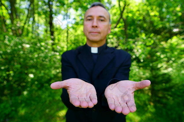 一位相貌英俊的天主教牧师正在高兴地欢迎我们。他自信地看着我们，平静地张开双臂。关注双手。