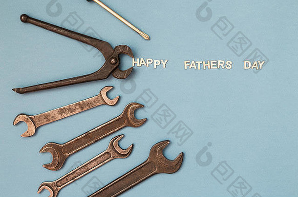 父亲节概念卡，灰色背景上印有人类工作工具，并刻有“父亲节快乐”字样。顶视图。