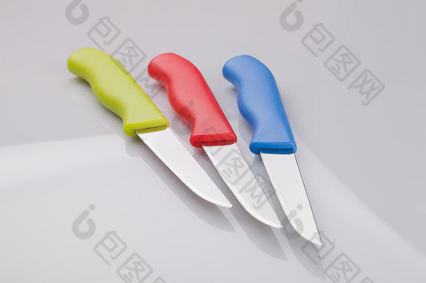 白色表面上的一套彩色厨房刀具。白色背景上隔离的厨房工具。