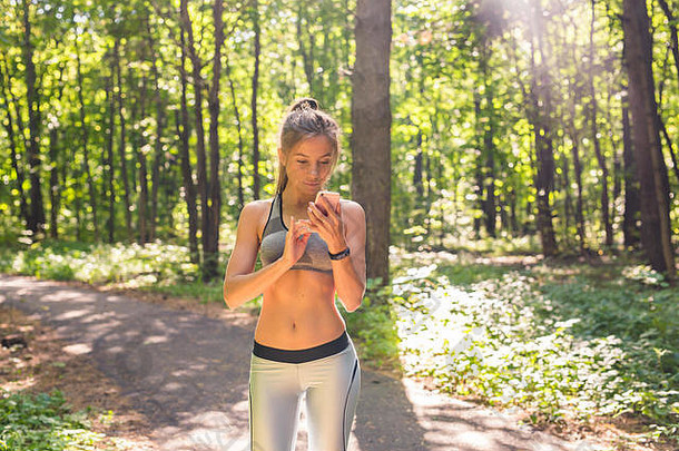 年轻的女运动员正在智能手表上检查健身进度。女跑步者使用健身应用程序监控训练表现。