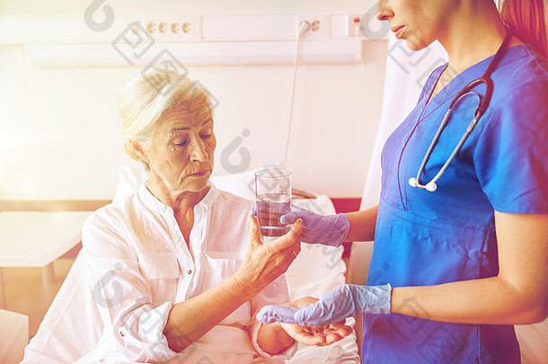在医院给老年妇女吃药的护士
