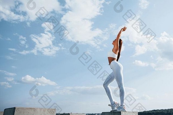 蓝色的天空摆姿势相机年轻的健身女人苗条的身体类型在户外