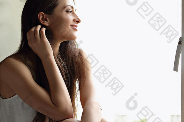 美丽的微笑积极的女人坐着窗口沉思的特写镜头肖像
