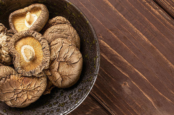 整批干蘑菇香菇放在灰色陶瓷板上，平铺在棕色木材上