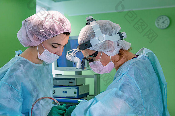 外科医生和他的助手在医院手术室对鼻子进行整容手术。鼻子整形，隆鼻。鼻整形术。