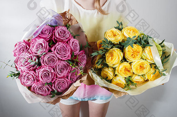 花商手里拿着一束玫瑰花。。粉红色和黄色。牛皮纸包装