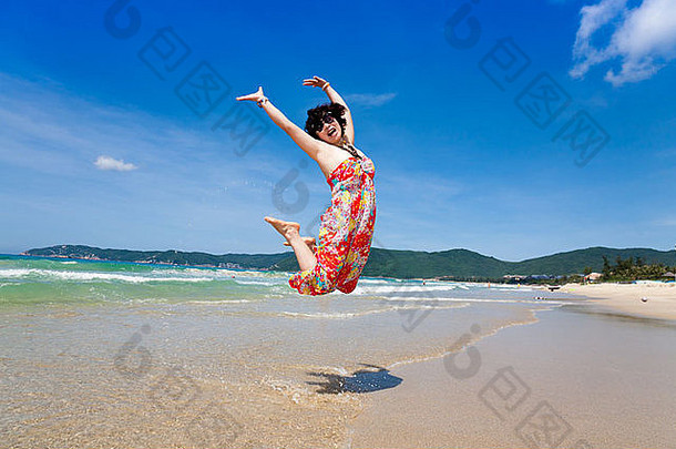 快乐女人在海滩上跳跃