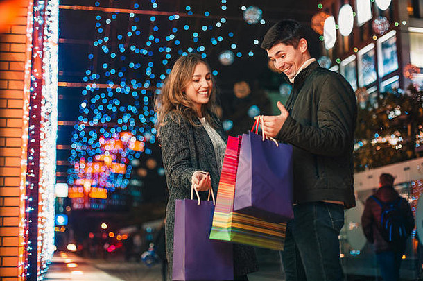 带着购物袋的幸福夫妇在城市背景中享受夜晚