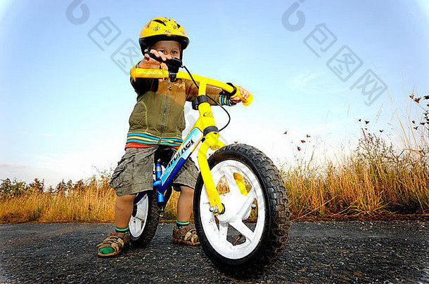 戴着自行车头盔骑着自行车穿过森林的小男孩