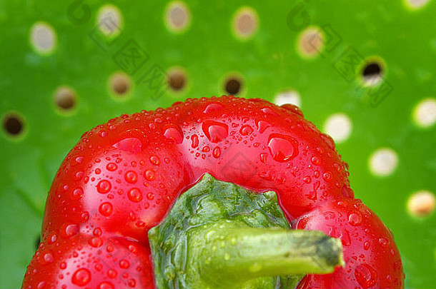 新鲜洗过的绿色滤网中的鲜红色甜椒。