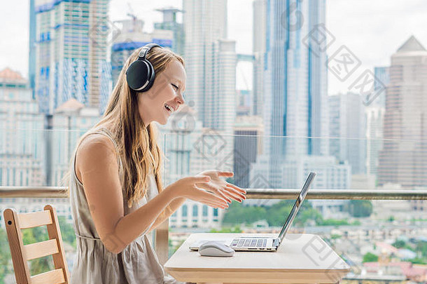 在大城市的背景下，一位年轻女子在阳台上教授外语或在互联网上学习外语。在线语言