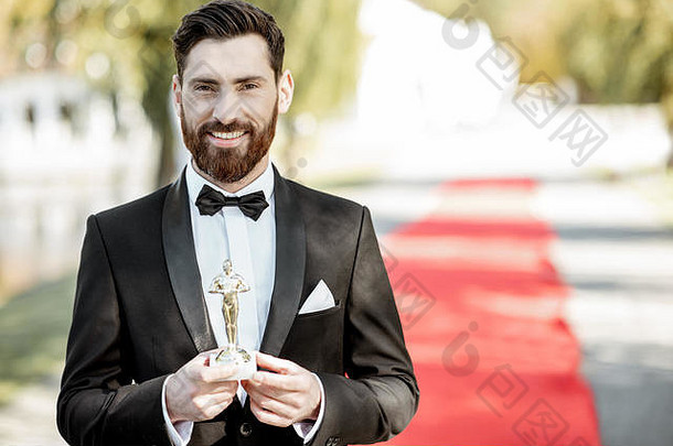 一位身着燕尾服的优雅男士的肖像，一位著名演员站在颁奖典礼的红<strong>地毯</strong>上