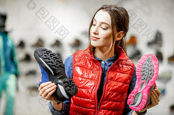 年轻女子在现代运动商店里选择登山鞋