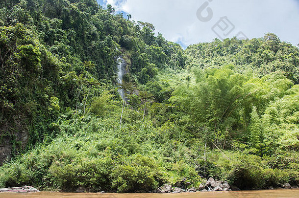 斐济苏瓦多云的天空下，雄伟的瀑布在热带雨林景观中流动