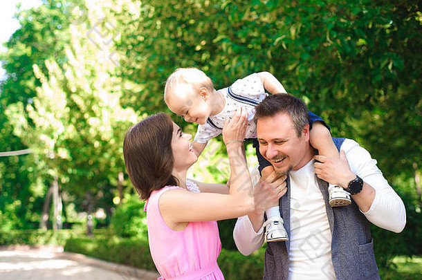 家庭，亲子关系，和人的概念-快乐的母亲，父亲和小男孩在夏季公园散步。