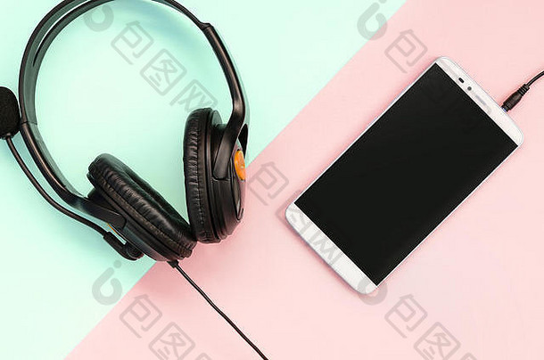 黑色的耳机智能手机谎言色彩斑斓的柔和的粉红色的背景音乐听概念可移植的技术平躺前视图