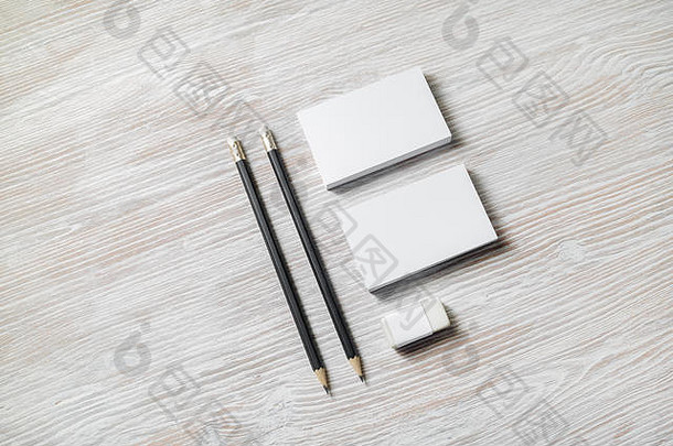 浅色木质桌子背景上空白名片、铅笔和橡皮擦的照片。
