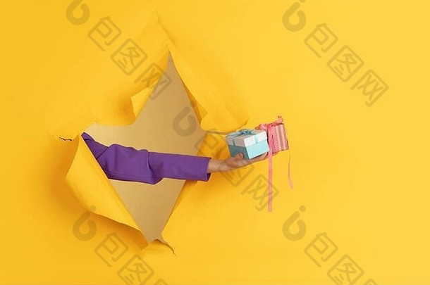 女手给粉红色的礼物惊喜撕裂黄色的纸洞背景打破breakthrought概念庆祝活动购物建议销售Copyspace促销活动折扣