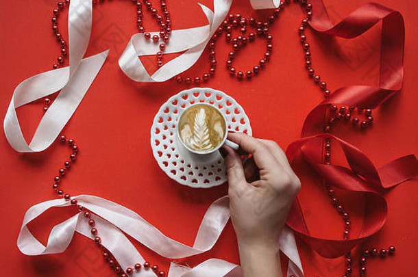 一个女孩手里拿着一杯鲜卡布奇诺咖啡，背景是假日背景。情人节或妇女节的概念。