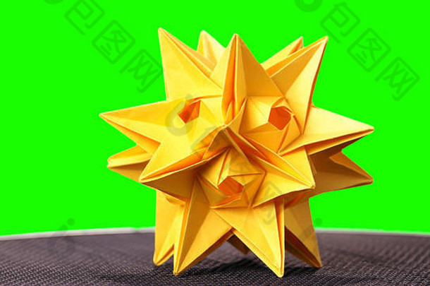 绿色背景上的黄星折纸雕像。