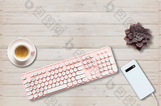 女办公桌。电脑键盘粉色，手机木质背景，复印空间