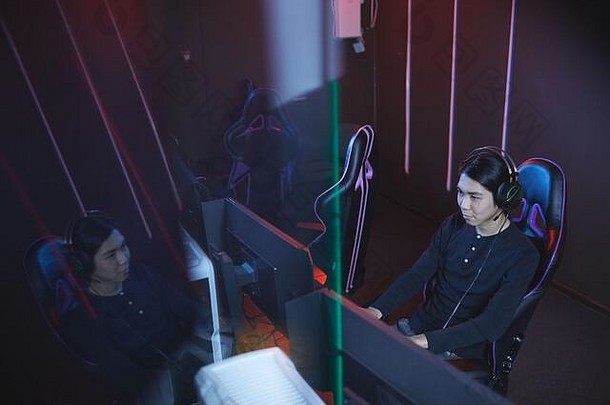 高角度观看亚洲年轻男子在未来网络室内使用电脑，空间