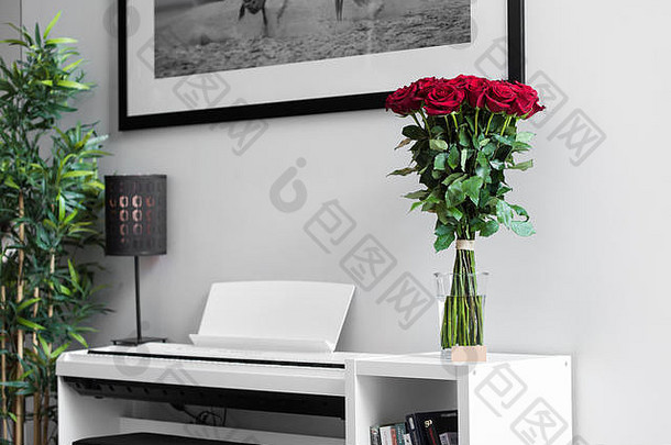 白色桌子上的一束红玫瑰，背景是白色钢琴