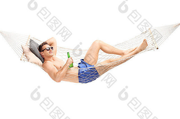 一个英俊的年轻人躺在吊床上，拿着一杯啤酒在白色背景上休息
