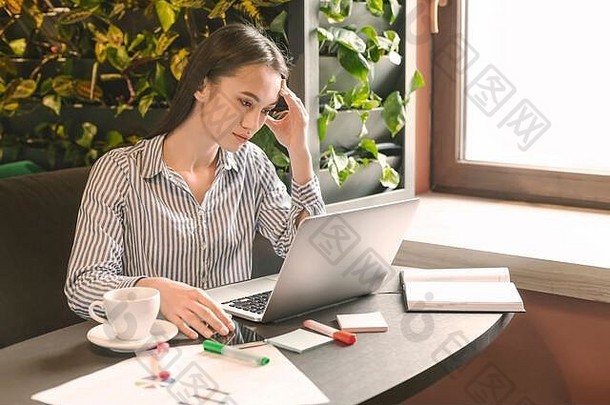 紧张的女商人坐在咖啡馆的笔记本电脑上分析数据