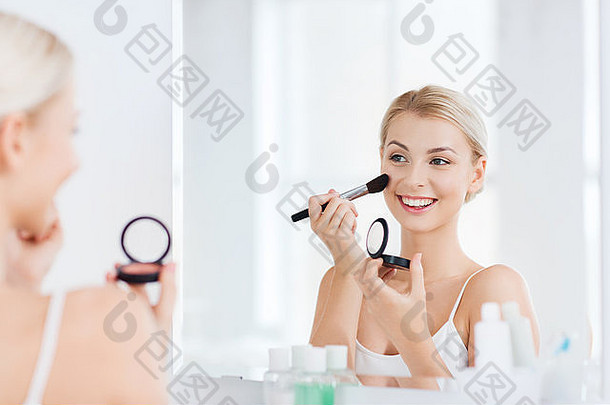 在浴室用化妆刷和腮红的女人