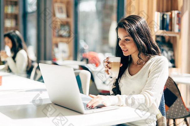 漂亮的黑发女人喜欢喝咖啡和使用<strong>笔</strong>记本电脑