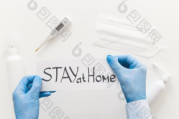 医生手拿手套持纸呆在家里呼吁停止传播冠状病毒或COVID-19流行