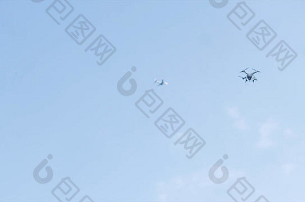 在他上方天空中飞行的无人机驾驶着飞机。在空中飞行的四翼无人机，装有数码相机，用于视频和<strong>照片制作</strong>