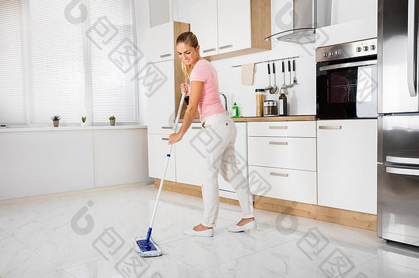 微笑的清洁服务妇女用拖把清洁家中厨房的地板