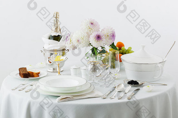白色背景上有盘子和鲜花的桌子